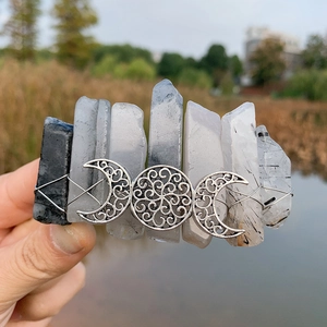 Detailed macro view of triple moon goddess charms and natural raw crystal quartz on hair clip