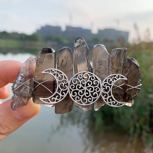 Macro shot of boho crystal hair clip featuring raw smoky stones and triple moon goddess symbol