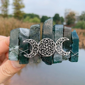 Macro detail of moss agate hair clip with silver triple moon goddess symbol in nature