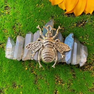 Macro shot of a bohemian crystal hair clip with a silver bee and gray quartz on moss