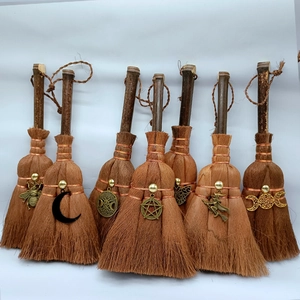Detail view of mini wicca altar brooms with unique vintage metal charms and natural fiber