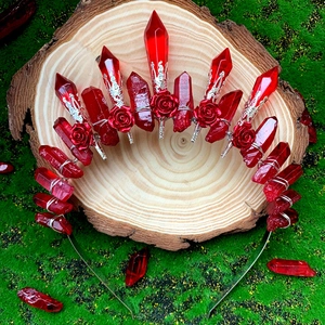 Couronne en cristal rouge avec roses métalliques et bandeau argent sur fond de mousse