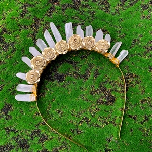 Détail d'un serre-tête couronne en cristal avec roses dorées sur fond de mousse