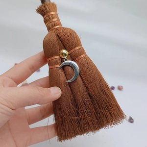 Detail of a handmade mini witch broom pendant featuring a silver crescent moon and crystal