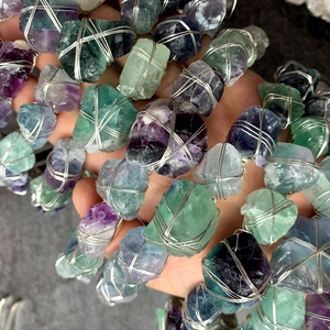 Dettaglio di pietre di fluorite grezza viola e verde avvolte a mano con filo d'argento