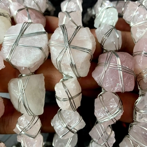 Dettaglio macro di quarzo rosa e cristallo bianco avvolti in filo d'argento lucido