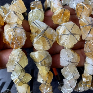 Dettaglio di pietre di quarzo giallo naturale avvolte in una rete metallica d'argento