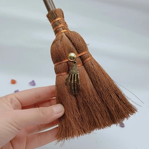 Detail of wicca mini broom car charm with bronze skull hand and fiber brush texture