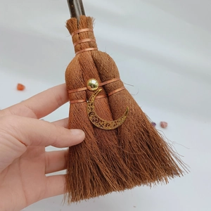 Macro shot of mini wicca witch broom with crescent moon charm and golden bead detail