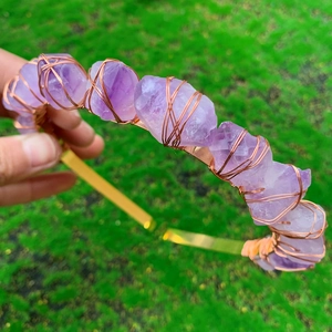 Dettaglio di pietre di ametista naturale avvolte in filo di rame su cerchietto dorato