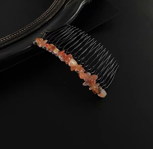 Detail view of 20-tooth black metal hair comb with natural orange-brown crystal stones