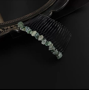 Macro view of green natural stone set on a 20-tooth black metal hair comb with vintage mirror