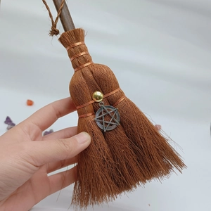 Detailed close-up of a mini handmade witch broom featuring a pentagram charm and crystal
