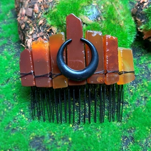 Pettine per capelli bohémien con cristalli ambrati e luna nera su sfondo di muschio verde