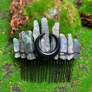 Dettaglio del pettine per capelli boho con cristalli e luna su sfondo di muschio verde