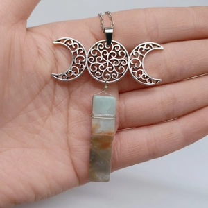 Detailaufnahme der Triple Moon Goddess Halskette mit Naturkristall auf der Hand