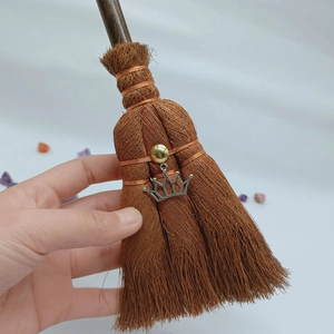 Macro detail of mini wicca broom pendant with silver crown charm and crystal bead