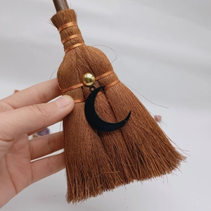 Macro view of mini wicca broom with copper wire, gold bead and black moon pendant detail