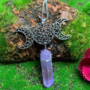 Detail showing triple moon symbol with purple crystal point on green moss background