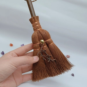 Macro detail of handmade mini witch broom pendant with crystal and metal branch charm