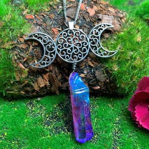 Detailed shot of Triple Moon goddess pendant with aura quartz on natural moss