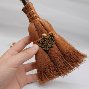 Close-up of handmade mini witch broom pendant with bronze butterfly and crystal detail