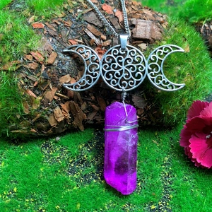 Detail of Triple Moon Goddess necklace with purple crystal on mossy tree bark