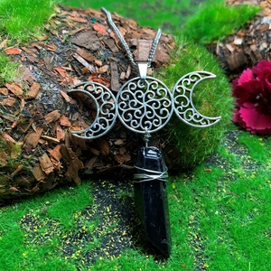 Close-up of triple moon necklace with crystal pendant and intricate hollow pattern