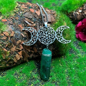 Detail of Triple Moon pendant with green crystal stone on a natural mossy wood background