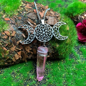 Handmade triple moon goddess necklace with pink crystal point on nature background