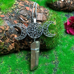 Detailed view of Triple Moon Goddess necklace with crystal point on natural mossy bark