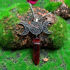 Triple moon goddess necklace with silver hollow pendant and red crystal on moss