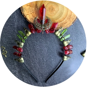 Gothic witch crown with red and green crystals, bronze skull and moon on dark stone background