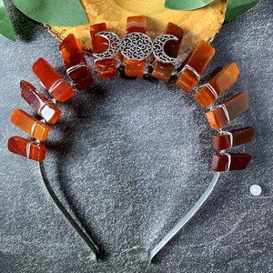 Detail of raw orange crystal moon crown with silver wire wrapping and goddess symbol