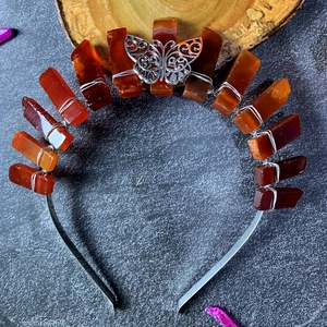 Détail de la couronne en cristal avec pierres orange et ornement papillon argenté