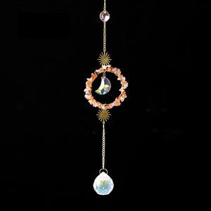 Detail of crystal suncatcher featuring orange gravel ring with sun and moon accents