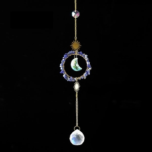 Close-up of a golden crystal suncatcher featuring a blue lapis lazuli ring and moon pendant