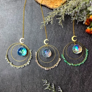 Detail of crystal suncatchers with gold metal moons and polished natural gemstone chips