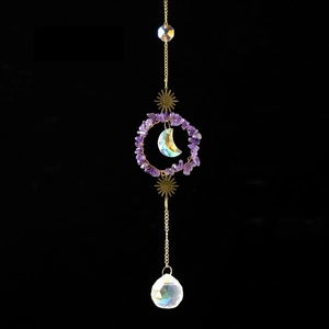 Detail of amethyst crystal suncatcher with golden moon and sun metal ornaments