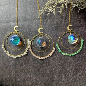 Three crystal suncatchers with natural stones and metal crescents on grey background