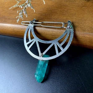 Macro detail of crescent moon hair pin with wrapped green crystal prism charm