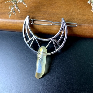 Detailed view of crescent moon hair clip with wire-wrapped raw yellow crystal pendant