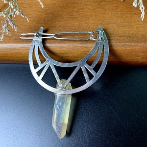Macro shot of silver crescent moon hair clip with a hexagonal yellow crystal pendant