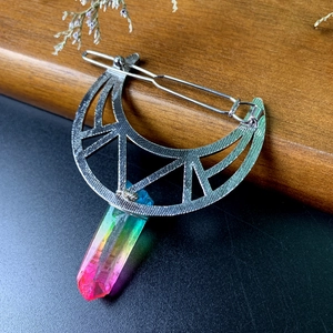 Detail of silver crescent moon hair clip featuring a colorful rainbow crystal point