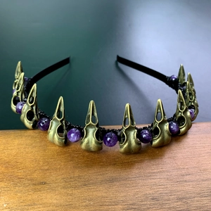 Macro shot of gothic raven skulls and purple crystal beads on a handmade headband
