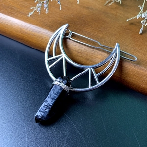 Detail of silver crescent moon hair clip with black crystal and wire-wrapped pendant
