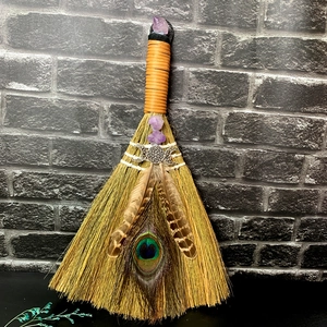 Handmade amethyst witch besom with peacock feathers and triple moon on gray wall