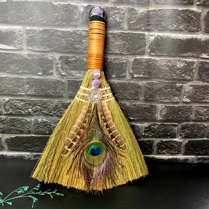 Macro shot of altar broom featuring peacock feathers and raw amethyst crystal detail