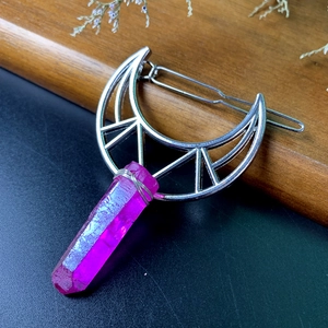 Detailed view of silver crescent moon hair clip with purple crystal on wood background