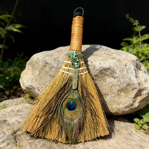 Close-up of altar ritual broom with a metal dragon, peacock feather, and green crystal